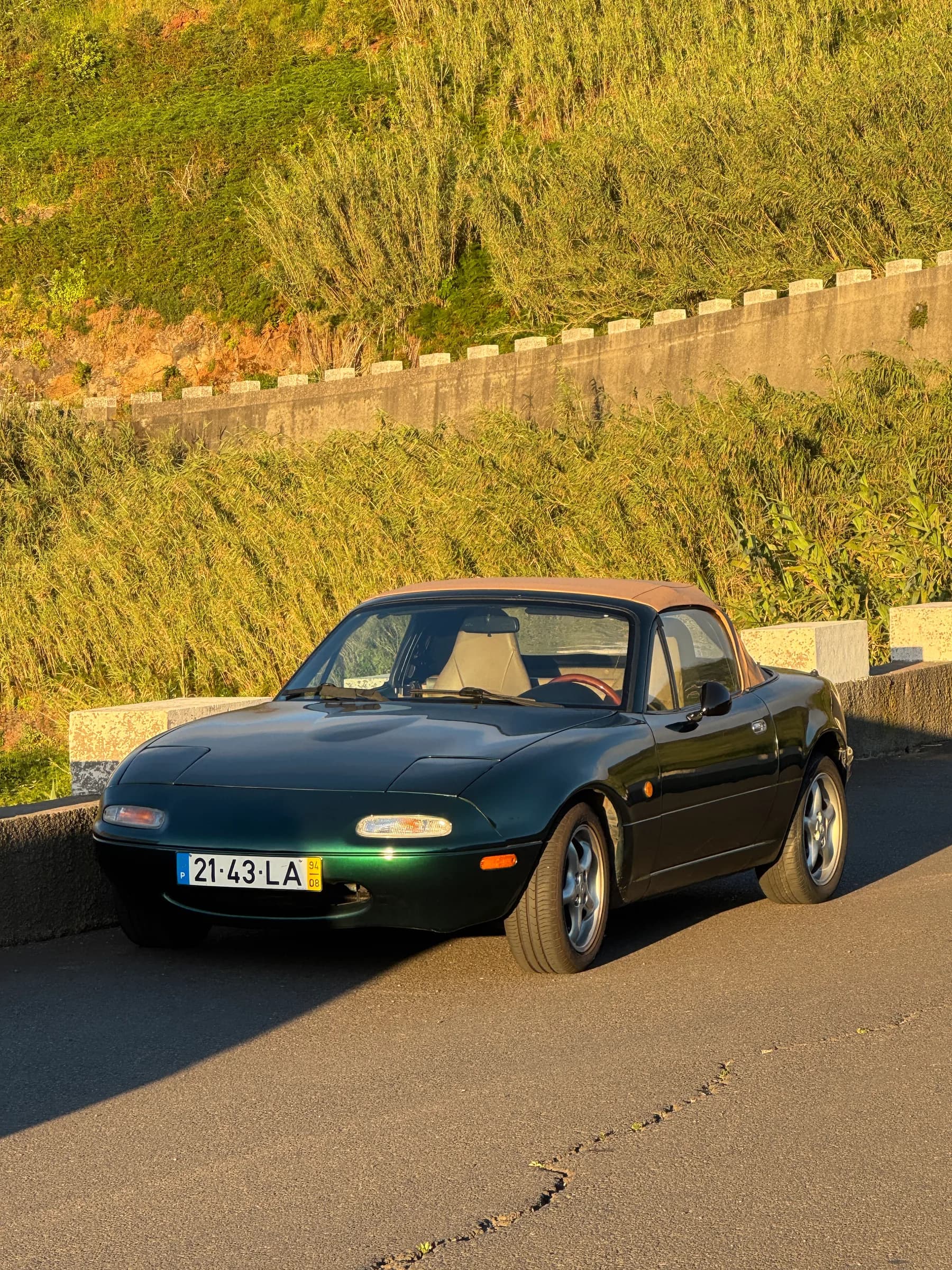 MX-5 com o soft-top bege levantado, à beira da estrada, com luz de fim de tarde
