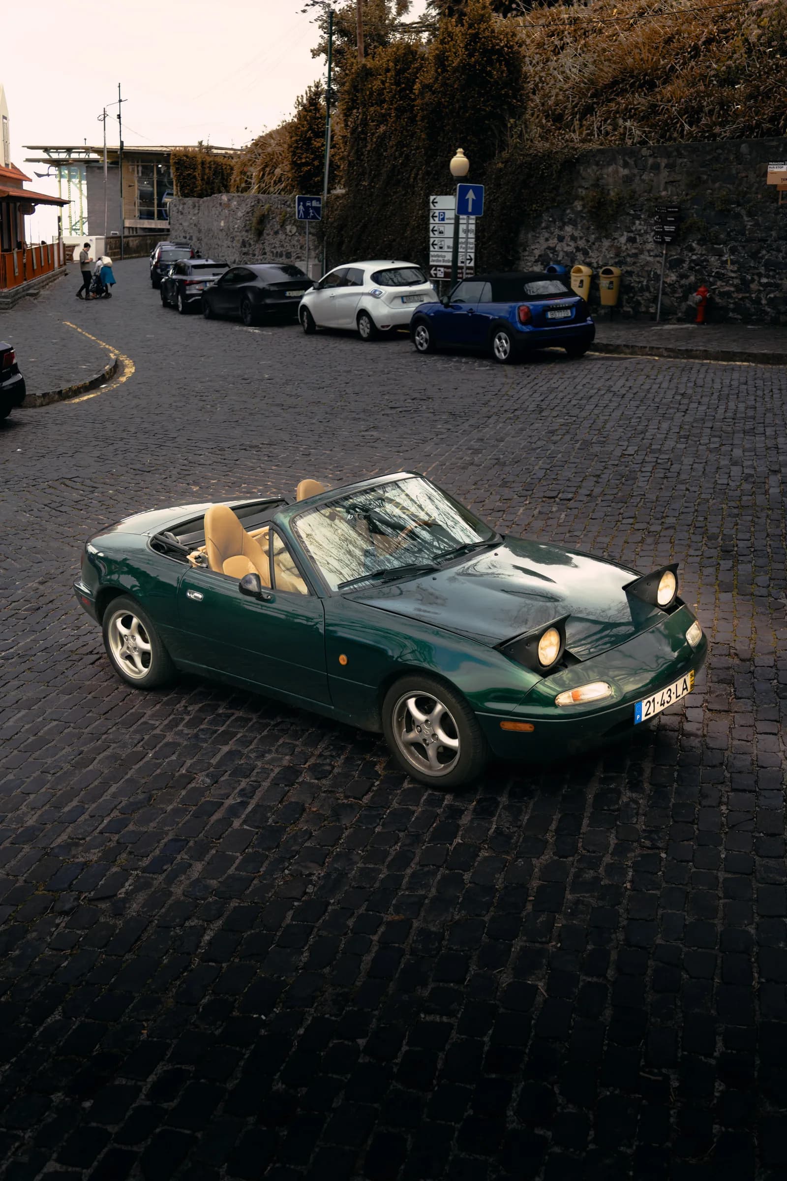 Mazda MX-5 de 1994, verde escuro, visto de três quartos com os faróis levantados
